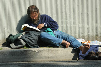 File photo: An unemployed and homeless man reads a bible near a freeway exit in Los Angeles on March 6, 2009.