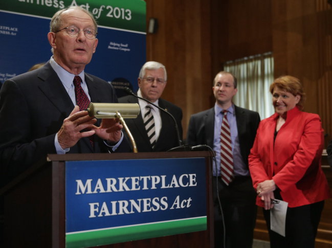Sen. Lamar Alexander, R-Tenn. (left), leads a news conference about the Marketplace Fairness Act on Tuesday. The legislation would provide states with the authority to require out-of-state retailers to collect and remit taxes on purchases shipped into the