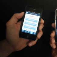 A Patt Morrison producer displays Mitt Romney's and Barack Obama's apps on iPhones