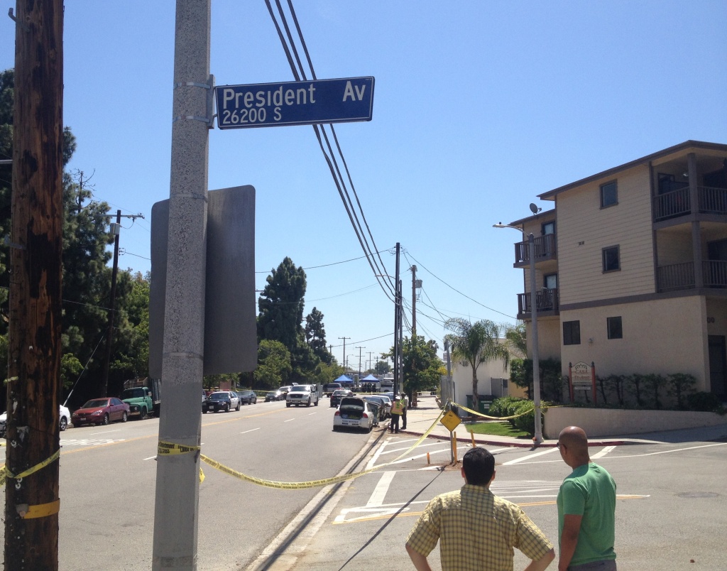 Two onlookers stare south on Anaheim Street in Harbor City Saturday, May 3, 2014 as LAPD investigators continue gathering evidence from the scene of a traffic collision that killed one officer.