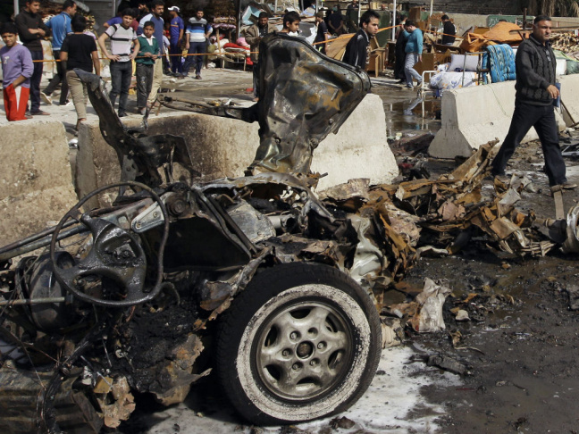 Iraqis inspect the scene of a car bomb attack in the Ameen neighborhood in eastern Baghdad on Sunday.
