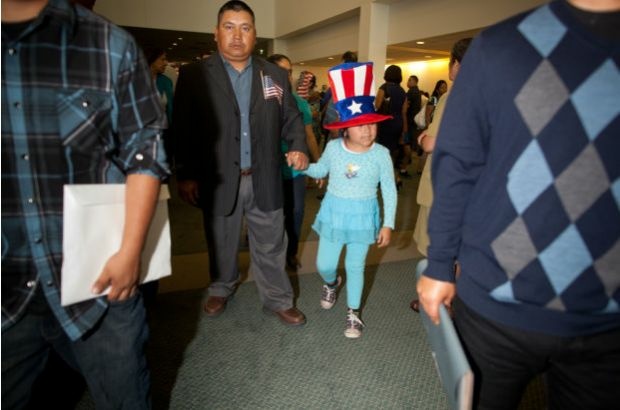 A newly naturalized U.S. citizen and his daughter - very much into the spirit of the occasion - leave a citizenship ceremony at the Los Angeles Convention Center, June 27, 2012.