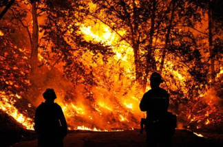 Los Angeles County fire fighters Pat Dunham (L) and Steve Bermau look on as the out of control Station Fire threatens a home on near Ocean View Drive in the La Canada Flintridge foothills above Los Angeles on August 29, 2009 in Los Angeles, California.