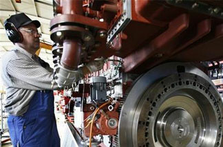 In ths Feb. 17,2009 file photo, an engine technician works on a vessel engine at the Caterpillar company in Friedrichsort near Kiel, northern Germany. More than half of the 15,000 people that Caterpillar Inc., maker of the signature yellow bulldozers and tractors, has hired this year were outside the U.S.