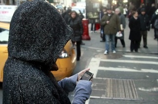 A pedestrian uses a phone by a crosswalk in New York City on Jan. 4, 2011.