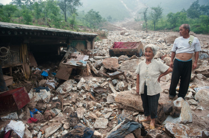 Two elderly residents stand by their hom
