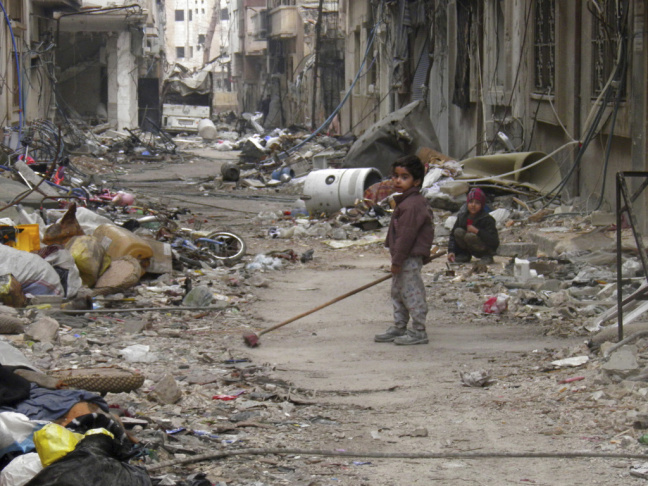 A child clears damage and debris in the besieged area of Homs on Sunday.