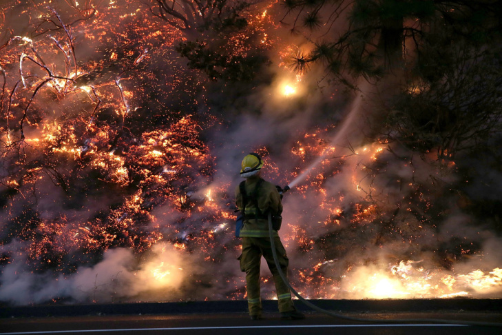 A firefighter uses a hose to douse the flames of the Rim Fire on Saturday near Groveland, California.