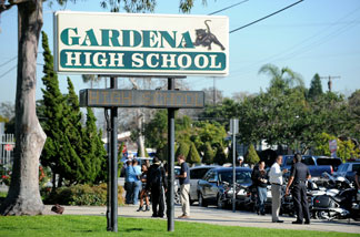 People walk past the entrance to Gardena High School in Gardena, California January 18, 2011 after two students were shot, one in the head, when a gun went off accidentally in a classroom.