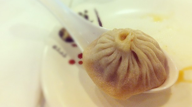 A xiao long bao, or soup dumpling, in a large spoon.