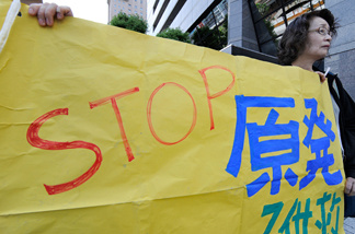 People hold a banner demanding the abolition of nuclear power plants in front of the headquarters of Tokyo Electric Power Company in Tokyo on May 8, 2011. Japanese trade and industry minister renewed its call for a halt to operations at a quake-warned nuclear plant, while denying the government will immediately reverse its nuclear power policy.