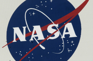 Birds fly past a NASA logo on the Vehicle Assembly Building at Kennedy Space Center.