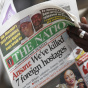 A man in Kano, Nigeria, reads a local newspaper Sunday that carries a story about the killing of seven hostages by a militant group.