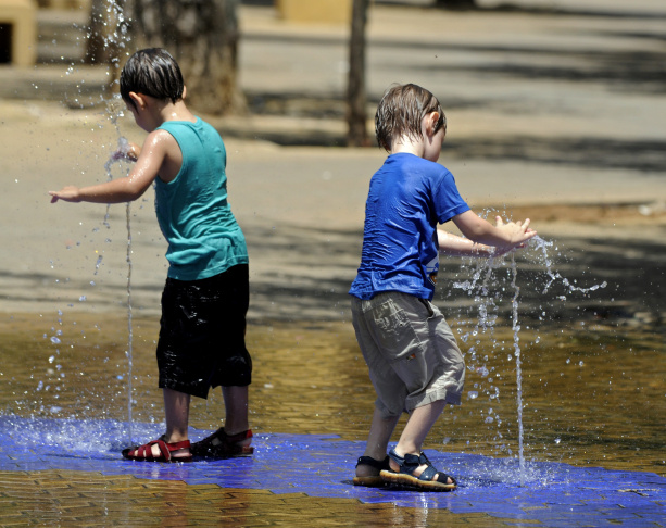 Children cool off by a fountain on a hot