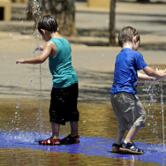 Children cool off by a fountain on a hot