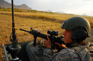 Spc. Riley Sheffield of Boise, Idaho, looks toward a tree line as insurgents fire on the convoy, just after the roadside bomb exploded. Soldiers from Charlie Company exchanged fire with insurgents for over an hour.