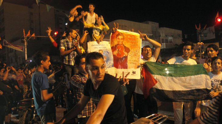 Palestinians dance while holding pictures of singer Mohammed Assaf, as they celebrate his Arab Idol victory along the streets of Gaza City Saturday.