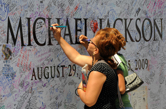 Fans sign a Michael Jackson poster covered in messages outside the Staples Center, which will be the site of a memorial service for musical legend after his recent death, in Los Angeles on July 6, 2009.
