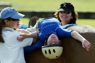 Eight year-old Michael Dedrick-Dwyer, who has cerebral palsy and autism, rides a horse with therapist Rebecca Reubens and a volunteer. A new study appearing in Pediatrics found racial differences in the ways children with autism used specialty care – for example, like that a neurologist would provide.
