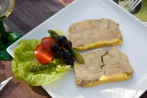 Slices of foie gras on a plate with garnish, close up