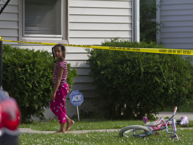 A young neighbor watches as police respond to a double homicide in Flint, Mich., on June 30, 2013. The alleged assailant was 13.