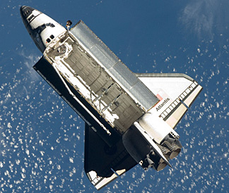 Space shuttle Atlantis flies around the International Space Station after undocking.