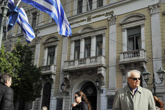 People walk by a National Bank of Greece