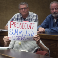 An attendee holds a sign during a town hall meeting at Pepperdine University's law school on toxic PCBs inside Malibu public schools; reporting by KPCC's Stephanie O'Neill on the issue was part of the investigative program "Reveal." 