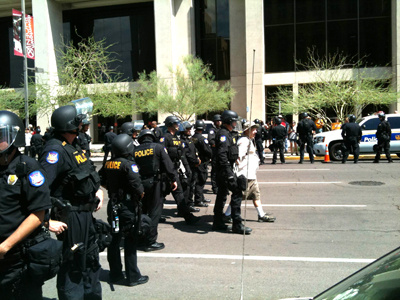 A man is escorted away from a scene by police in downtown Phoenix during demonstrations over Arizona's controversial immigration law on Thursday, July 29, 2010. About two dozen SB1070 opponents refused to disperse after Phoenix police declared an unlawful assembly. Police began arresting protesters at 11:50 a.m. The arrests were peaceful.