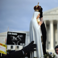 A marcher places a crown atop a statue o