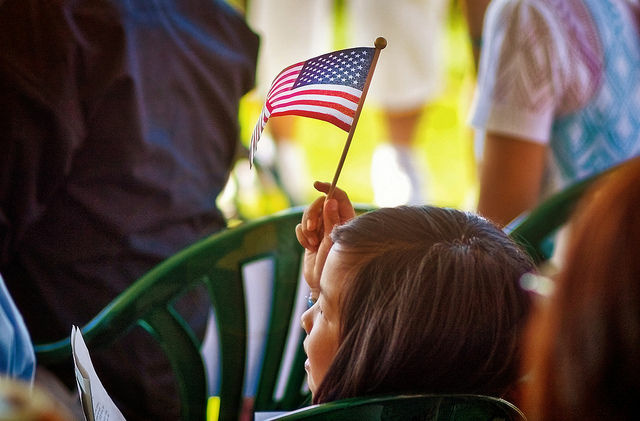 A girl waves the flag at a naturalization ceremony, July 2010