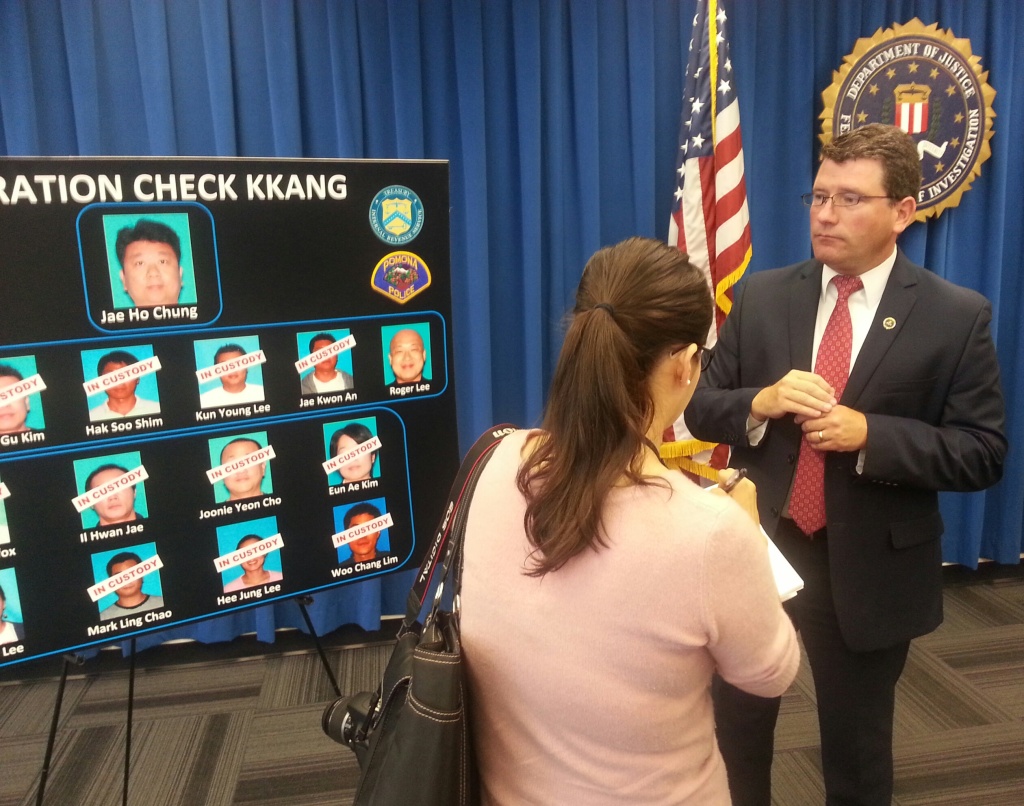 FBI special agent Timothy Delaney stands near a poster board depicting the alleged perpetrators of a fraudulent check passing ring that targeted Korean Americans.