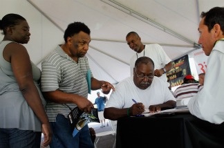 Job seekers speak with a construction company recruiter as they and others look for construction work.