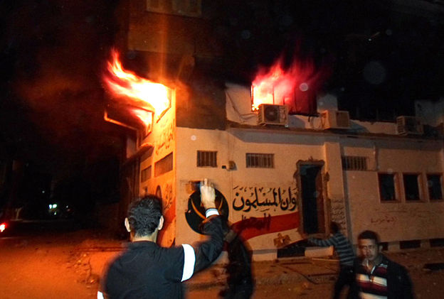 Egyptian protesters stand outside the burning office of the Muslim brotherhood in Ismailia, Egypt on Wednesday.