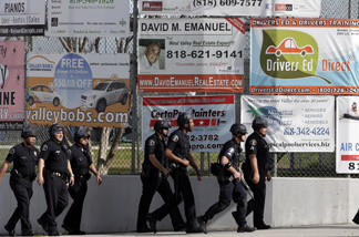 A group of police officers search outside El Camino Real High School in the Woodland Hills section of Los Angeles, Wednesday, Jan. 19, 2011.