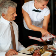 Young waitress shows the menu to mature couple