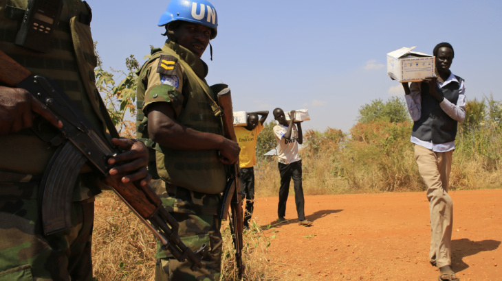 Troops sent to South Sudan by the U.N. watch as men walk to a camp for refugees near Juba, the nation's capital.