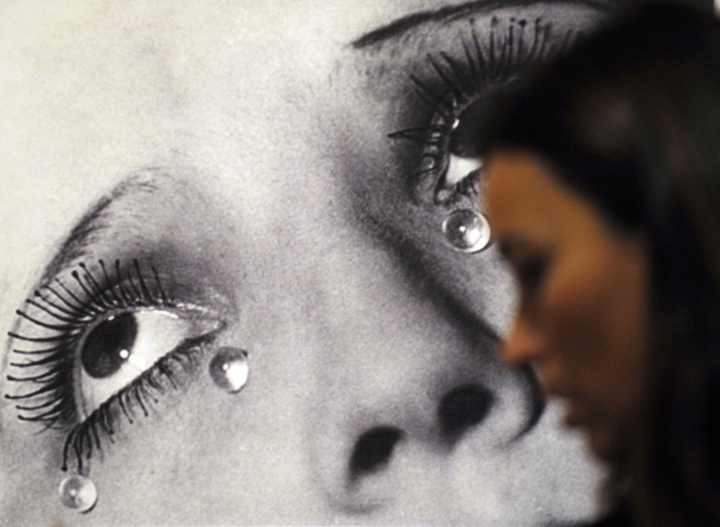 A visitor looks at the photo "Tears" by