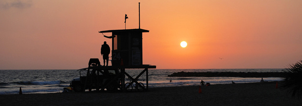 A lifeguard at a lifeguard tower at sunset in Newport Beach. The tradition of sitting around a bonfire at sunset may be banned from the beach.