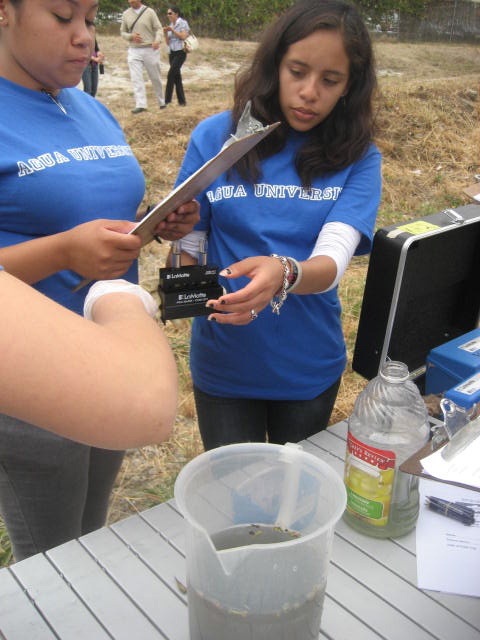 Youth conservation corps members test water near a soft-bottomed stretch of Compton Creek. Local officials announced the purchase of a 4-acre parcel of land here as part of a larger collaboration to revitalize the Los Angeles River.