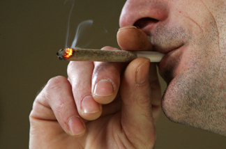 A man smokes a cigarette of marijuana.