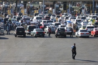 A member of the US Border Patrol walks behind the line of cars waiting to enter the United States from Mexico at the San Ysidro Port of Entry.