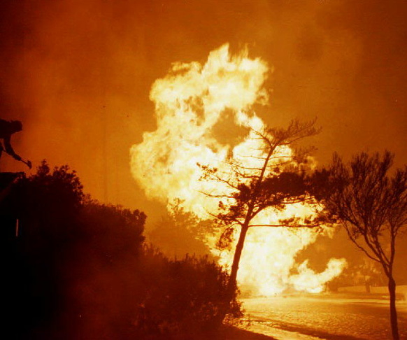 A fireman (L) atop a house tries to fight an out o