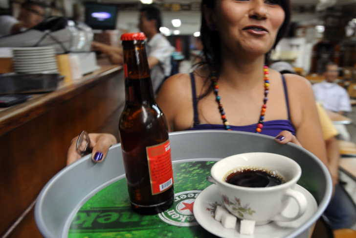 A waitress takes a coffe and a beer to a