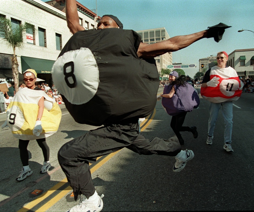A teenager dressed as the eight-ball in a game of pool runs through the Pasadena streets during last year's Doo Dah Parade.