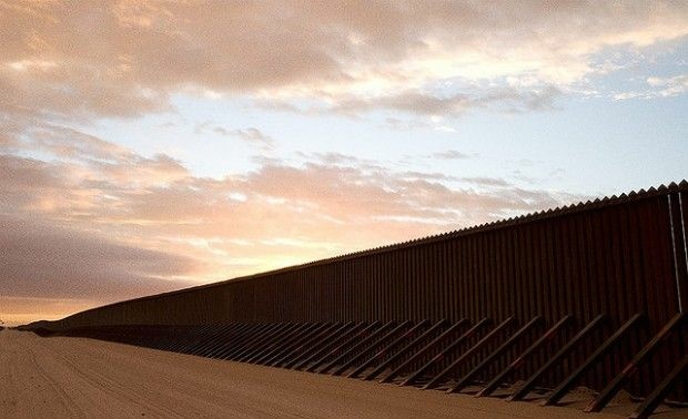 A stretch of border fence through the desert, Imperial Sand Dunes, California.