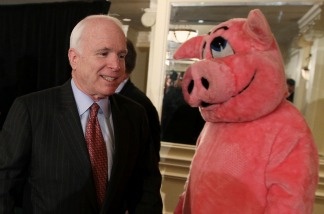 Sen. John McCain (R-Arizona), walks past someone in a pig costume during a news conference on April 14, 2010 in Washington, D.C. The news conference was held to release the annual '2010 Congressional Pig Book', which is a report on pork barrel spending in the federal budget.