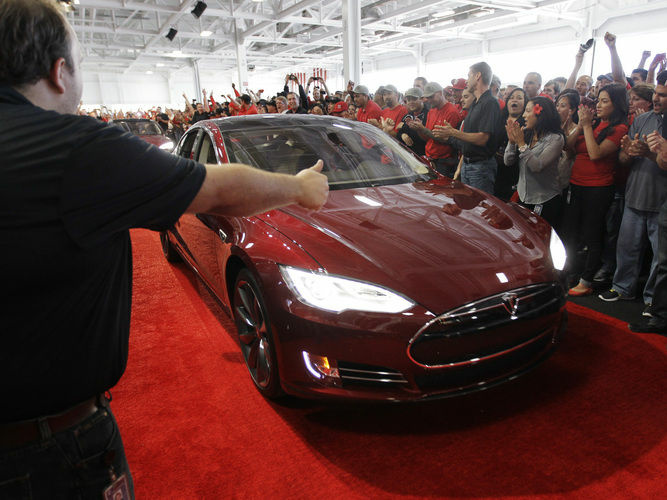 Tesla workers cheer on one the first Tesla Model S cars sold during a rally at the Tesla factory in Fremont, Calif., in June. The company is now unveiling a new network of refueling stations for the vehicles.