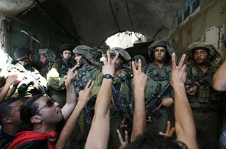 Israeli soldiers block foreigners, left wing Israelis and Palestinians as they protest against the Jewish settlement, close to an Israeli checkpoint located at the entrance of the West Bank city of Hebron, leading to the Jewish settlement of Beit Romano on July 3, 2010.