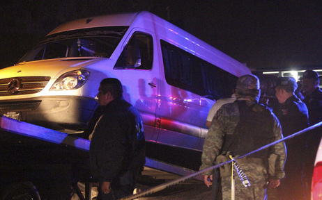 Police officers and soldiers stand around a white van containing the dead bodies of several man while it is being hauled onto a tow truck in San Luis Potosi on Thursday, August 9, 2012.